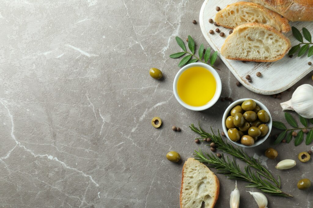 Concept of tasty eating with olive oil on gray textured table